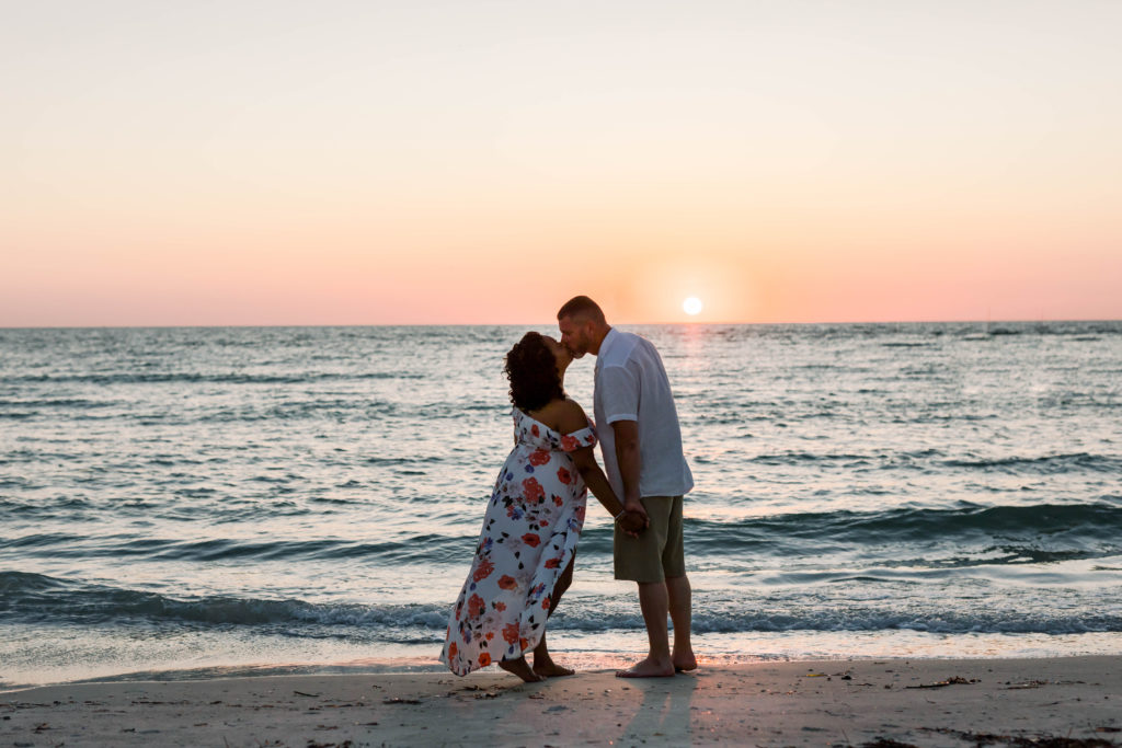Husband and wife are kissing before sunset on clearwater beach.