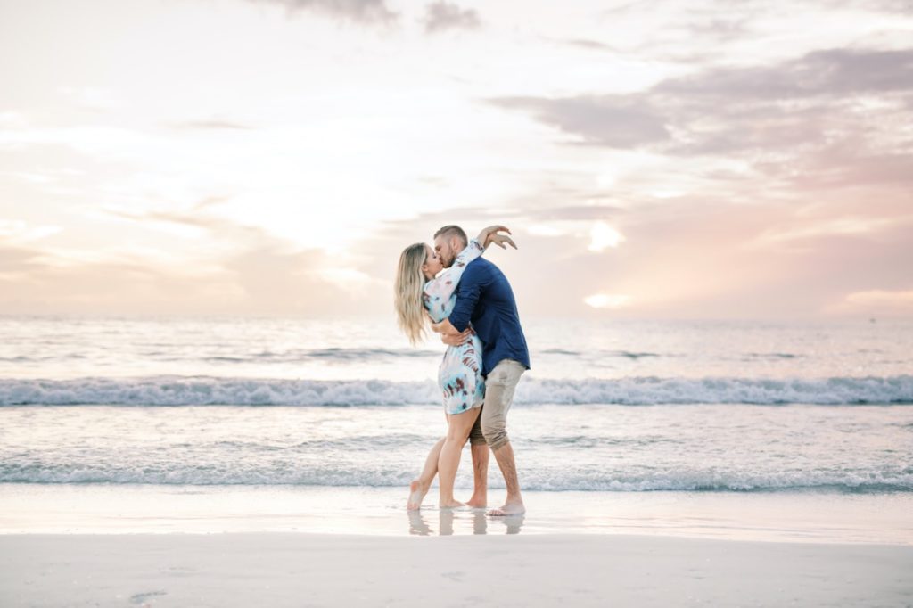Couple kissing on their engagement at the beach sunset.