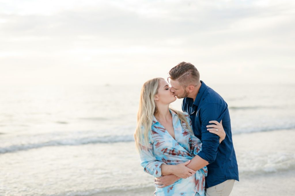 Cute couple kissing on their sunset beach engagement session