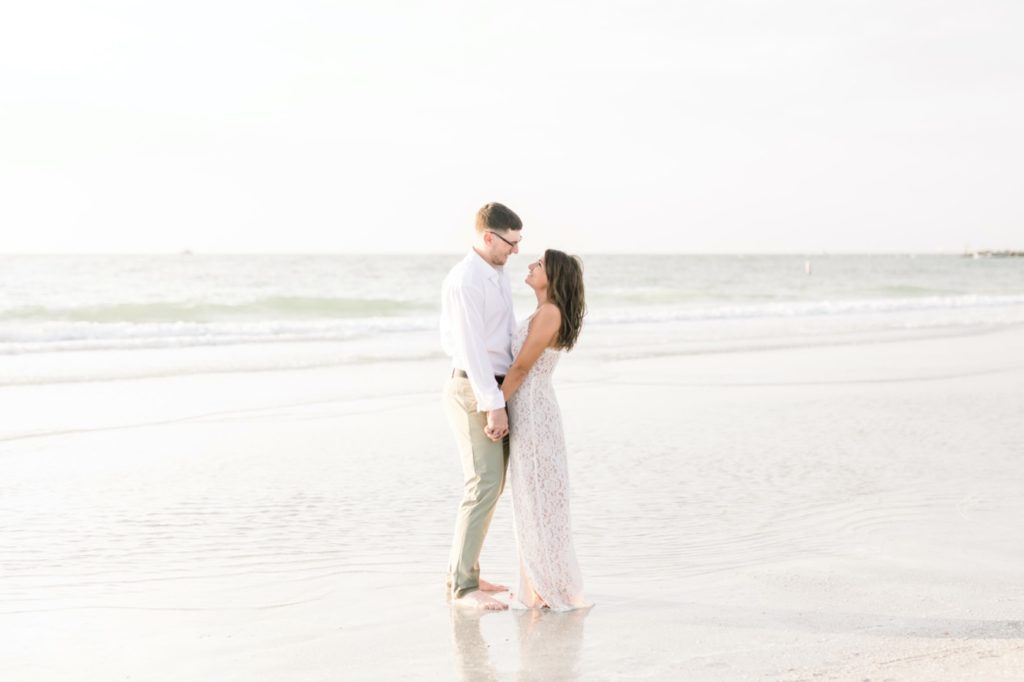 Gorgeous couple looks at each other on the beach on their fall engagement 