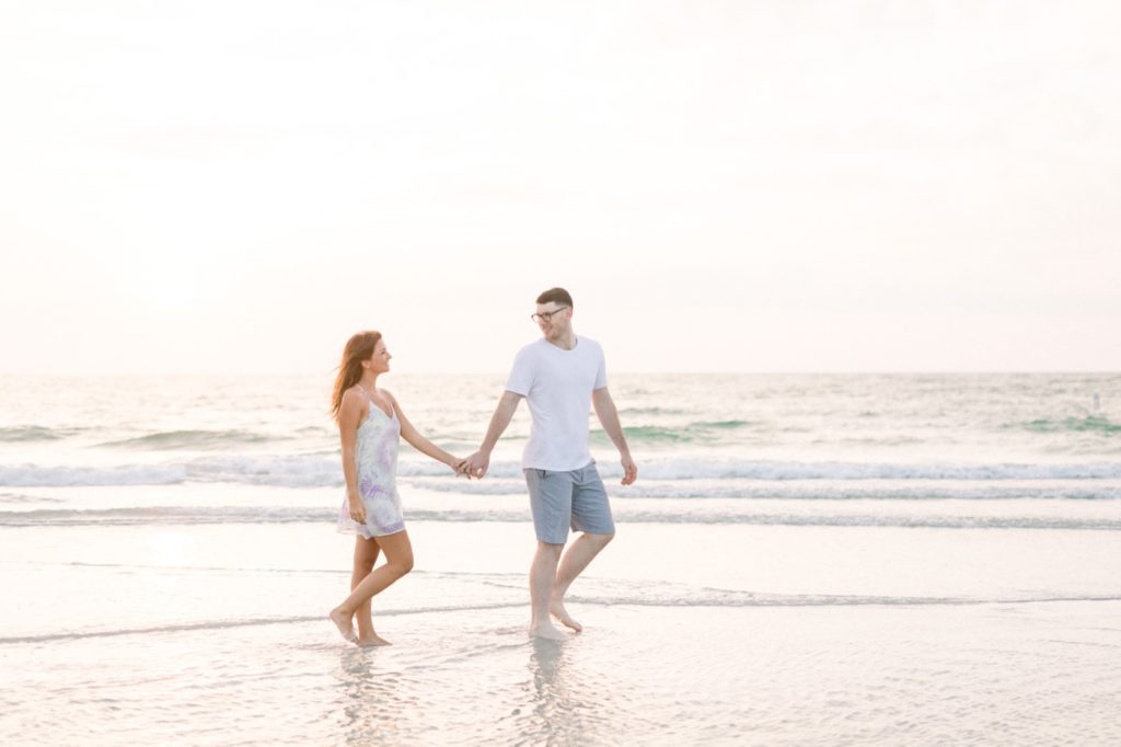 couple is walking at their fall engagement session on sand key beach