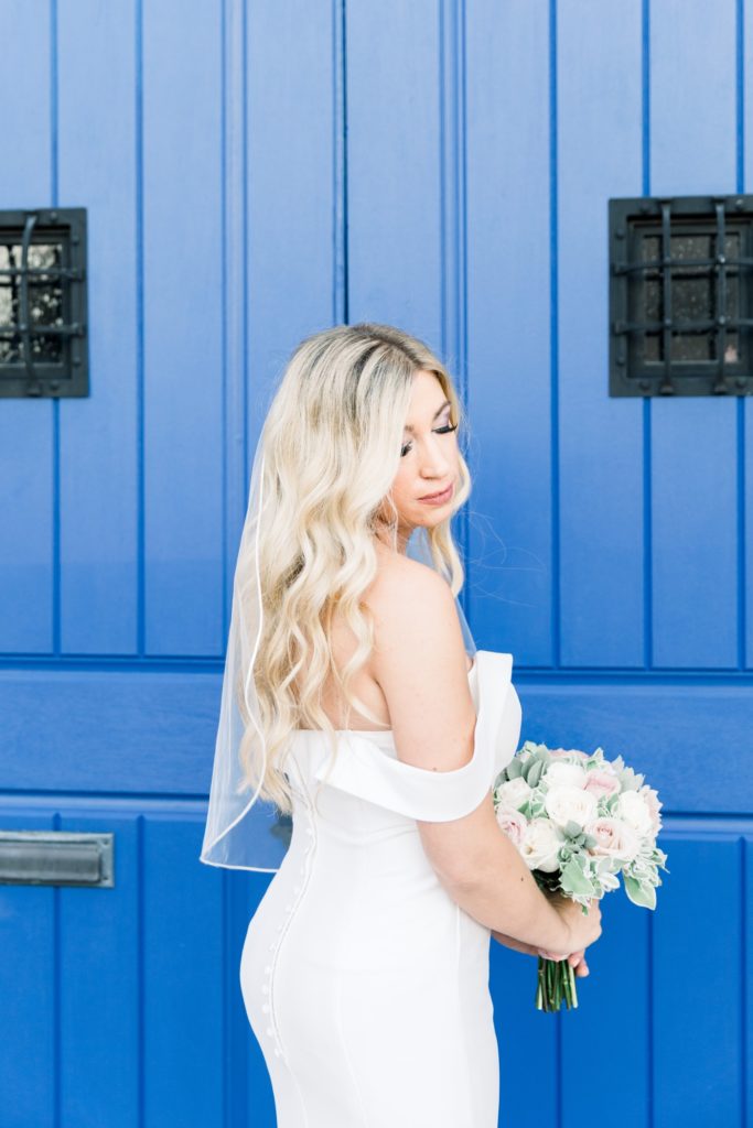 Bride is holding bouquet in front of the blue door at Rialto Theatre Wedding Venue Downtown Tampa