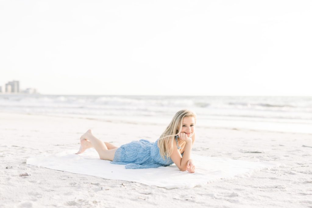 A girl is laying down on the sand.