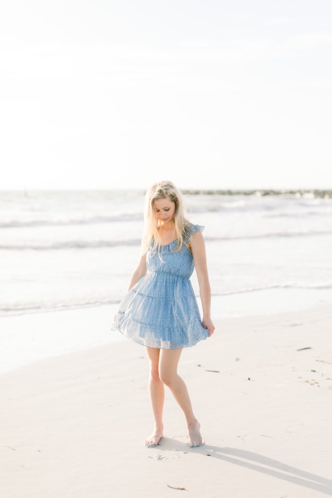 A girl is twirling her dress on the beach.