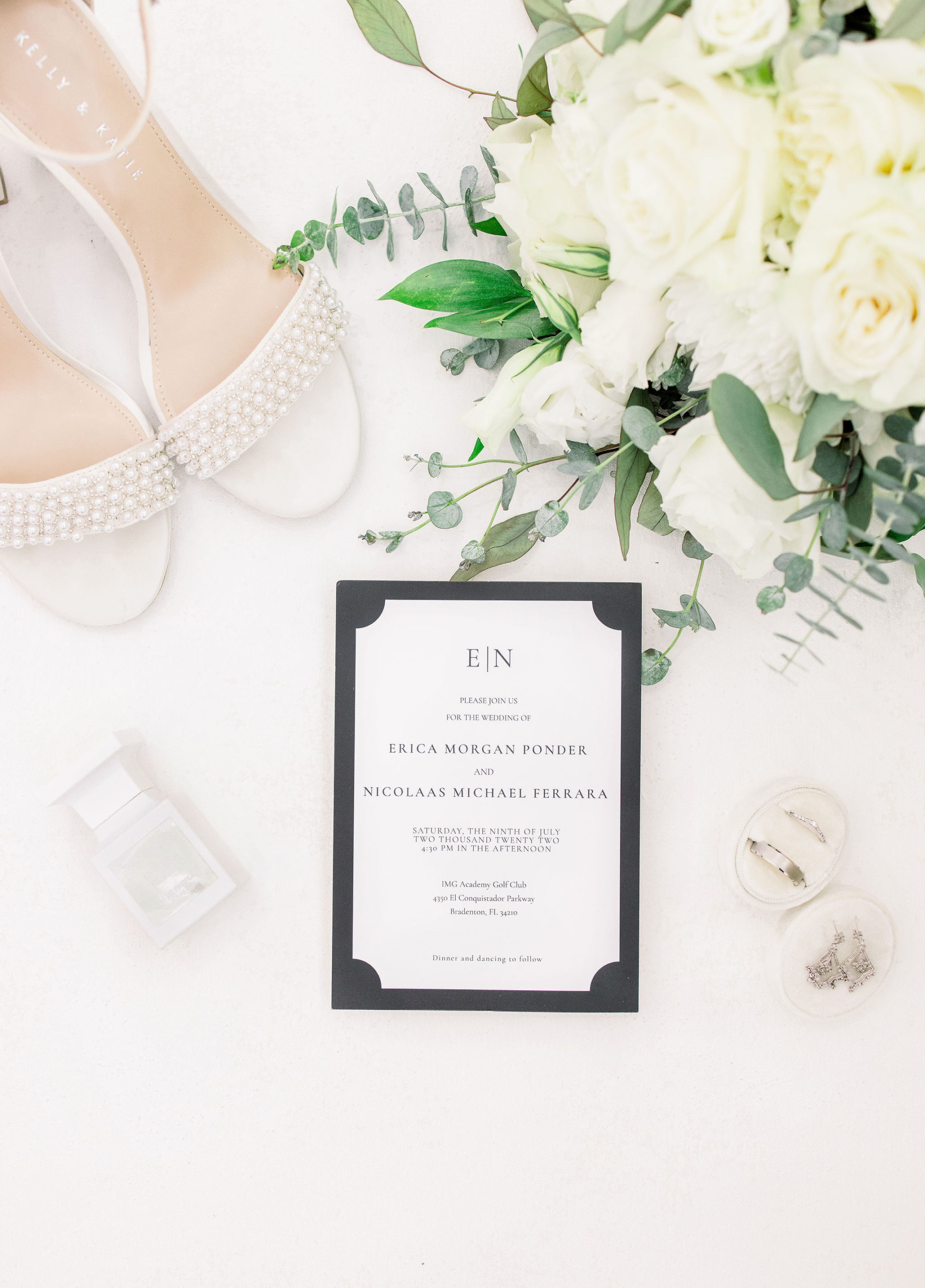 Wedding flat lay portrait with a wedding invitation, bridal shoes, bouquet, and wedding rings by Jommy Photography. Wedding detail flatlay portrait for a classic and timeless wedding in Bradenton, Florida.
