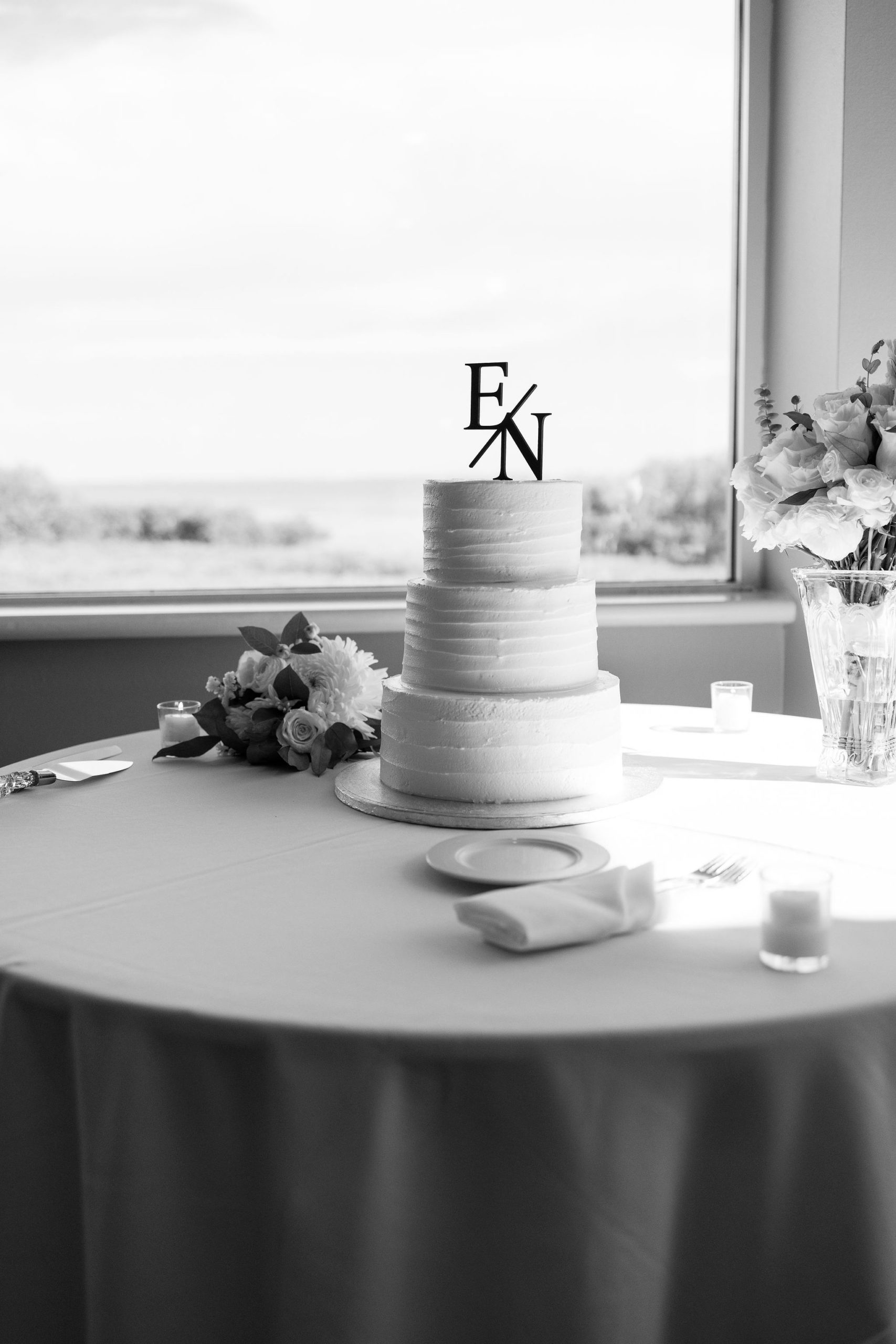 Black and white portrait of a modern wedding cake that is a three tier buttercream ruffle cake by Jommy Photography. Simple three tier buttercream wedding cake for a wedding at the IMG golf course in Florida.
