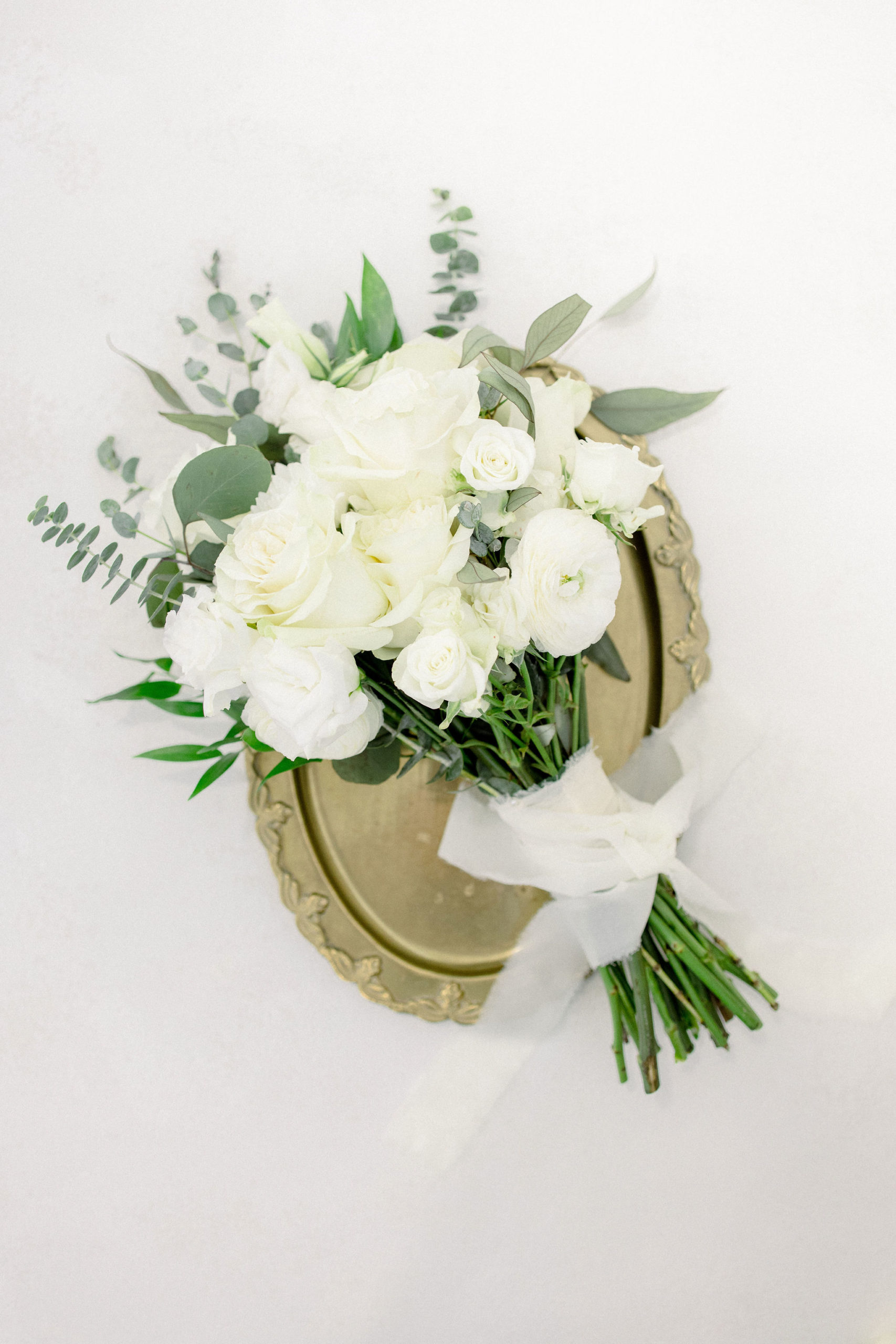 Wedding Photographer Jommy Photography captures a portrait of an all white and green bridal bouquet. White rose bouquet with silver dollar accents. Bridal bouquet flatlay portrait by Jommy Photography.
