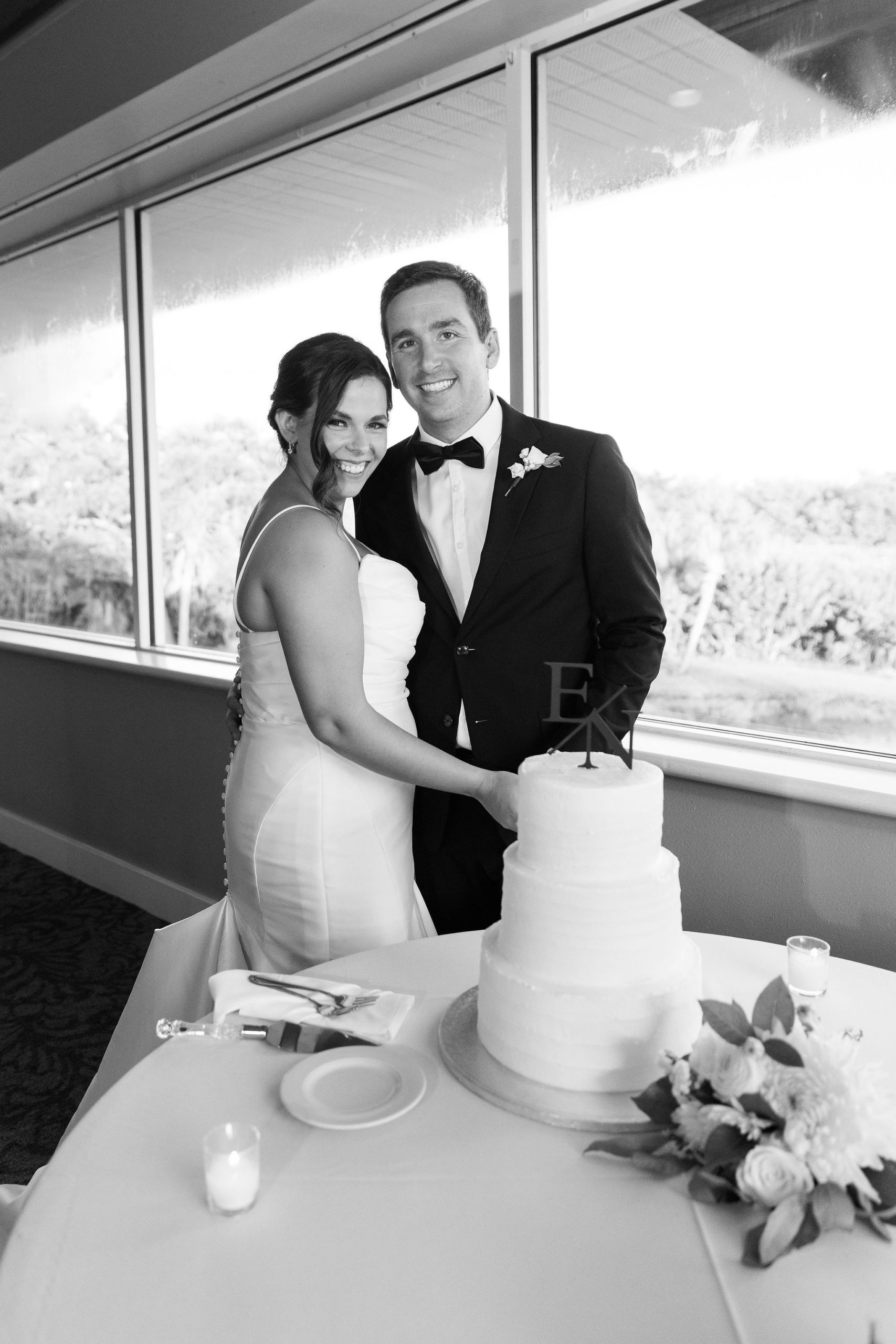 A bride and groom cut the wedding cake on their wedding day in Bradenton, Florida at a Golf Course by Jommy Photography. A wedding photographer in the Bradenton area with a timeless and classic vibe.
