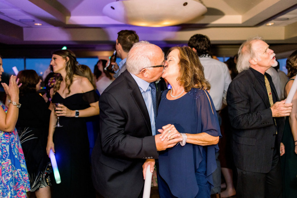 At the wedding after party Jommy Photography captures an older couple holding hands and kissing on the dance floor. Wedding reception guest pictures for a wedding in Bradenton, Florida by Jommy Photography.
