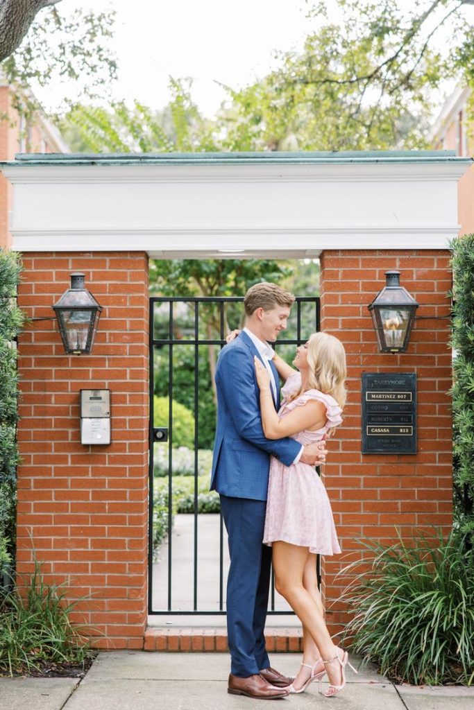 Outside a brick gate in Florida a couple of hugs by Jommy Photography a professional. old style house background #JommyPhotography #JommyCouples #FloridaCouplesPhotography #ProfessionalPhotographer #beachphotographer #couples #romanticcouples