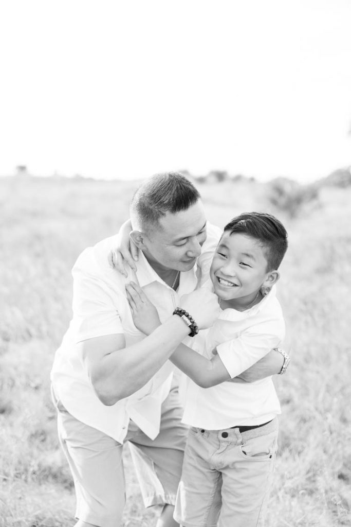A black and white portrait of a father wrestling with his boy by Jommy Photography. father and son portrait wrestling #JommyPhotography #JommyFamilies #FloridaFamilyPhotography #Familyphotographers #professionalphotographers #familyportraits